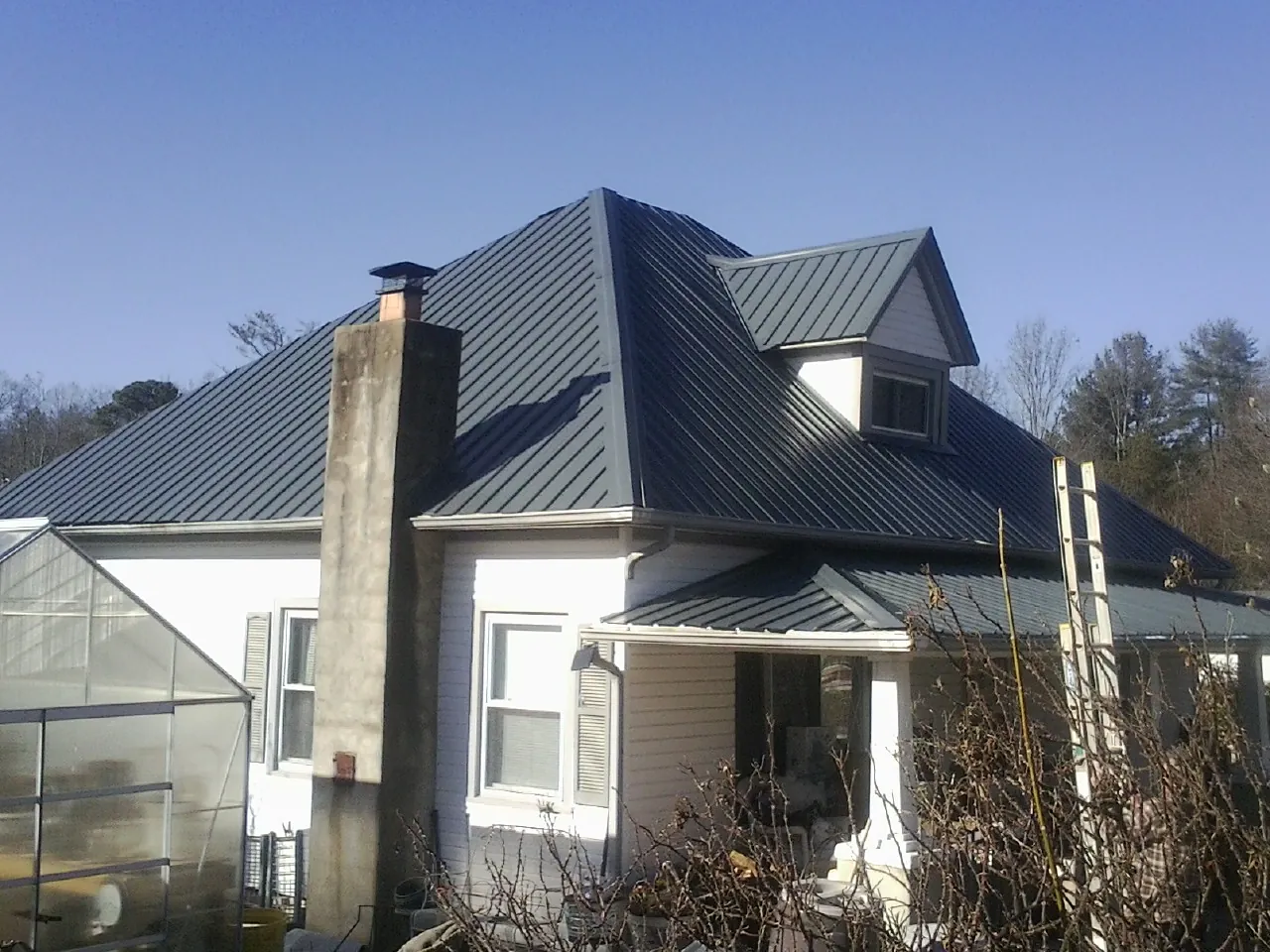 Dark blue standing seam metal roof on a white farmhouse with dormer — Slate & Tile Roof Repair by Roofing Brothers in Valley Village