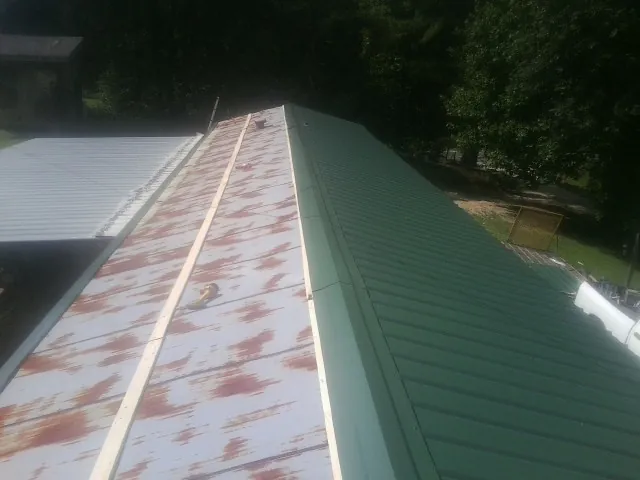 Old rusted panels beside newly installed green metal roofing — Wind Damage Roof Repair by Roofing Brothers in Valley Village