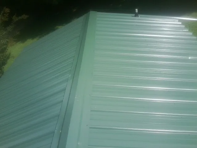 New green metal panels meeting at the ridge of a roof — Flat Roof Repair work by our crew in Valley Village