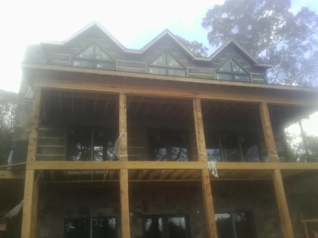 Dormers and porch framing on a large log home under construction — Roof Coating work by our crew in Valley Village