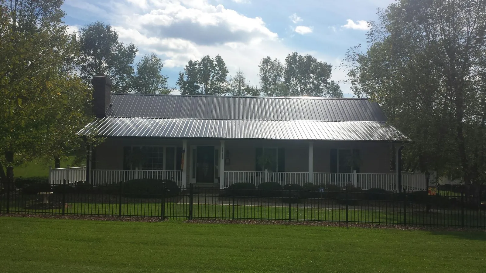 Gray metal roof on a brick ranch with a full width front porch — Gutter Guard Installation work by our crew in Valley Village