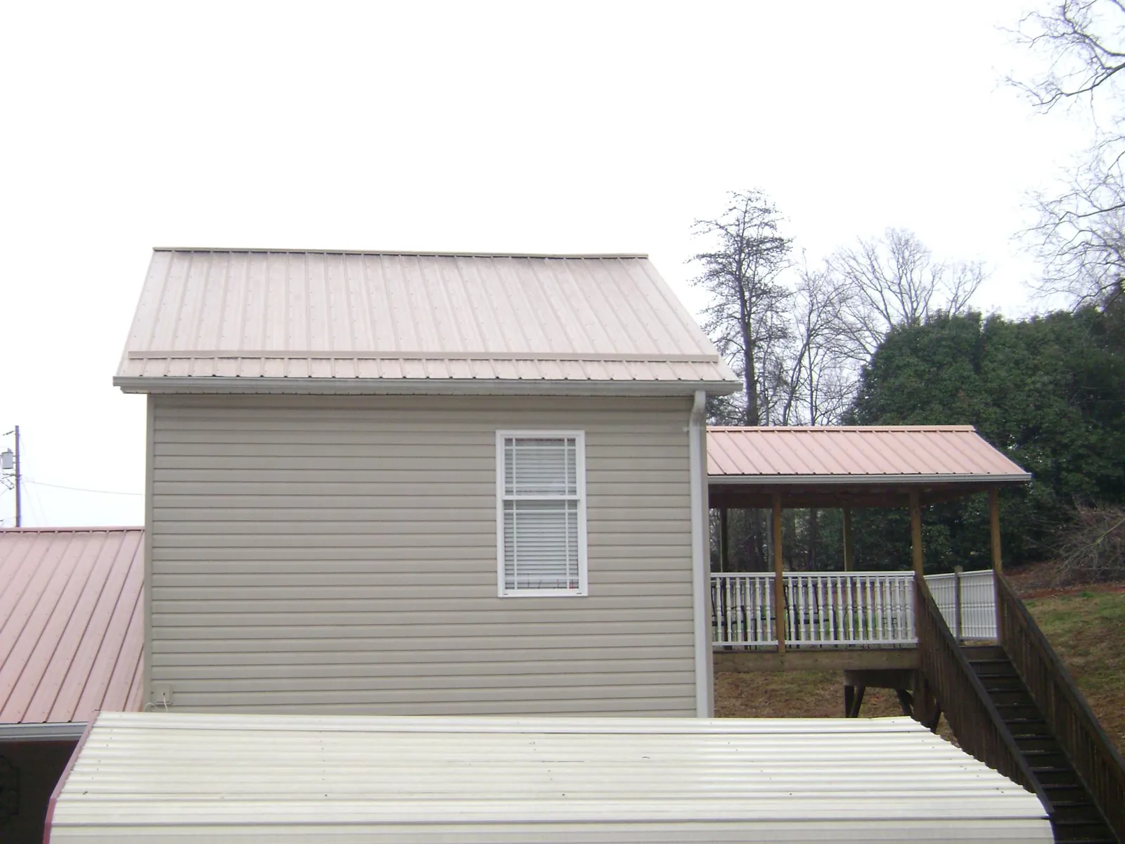 Tan metal roofs on a two story addition and attached porch, from a Roof Replacement job in Valley Village