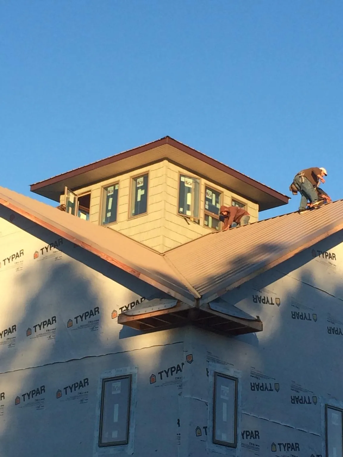 Roofers working around a rooftop cupola on a new metal roof at sunset — Roof Waterproofing in Valley Village by Roofing Brothers